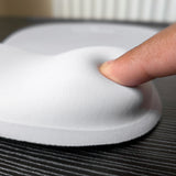 Doigt qui appuie sur le repose-poignet en mousse du tapis Ergozone gris